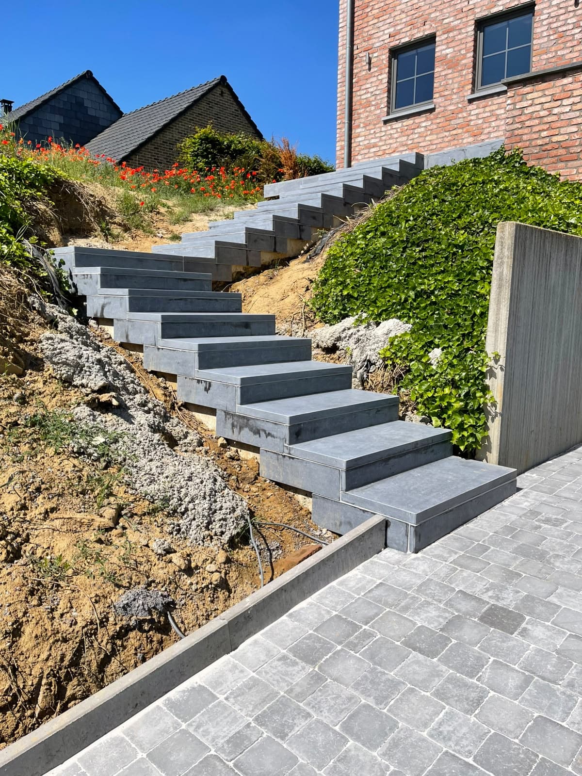 Escalier de jardin en pierre bleue entre deux talus plantés