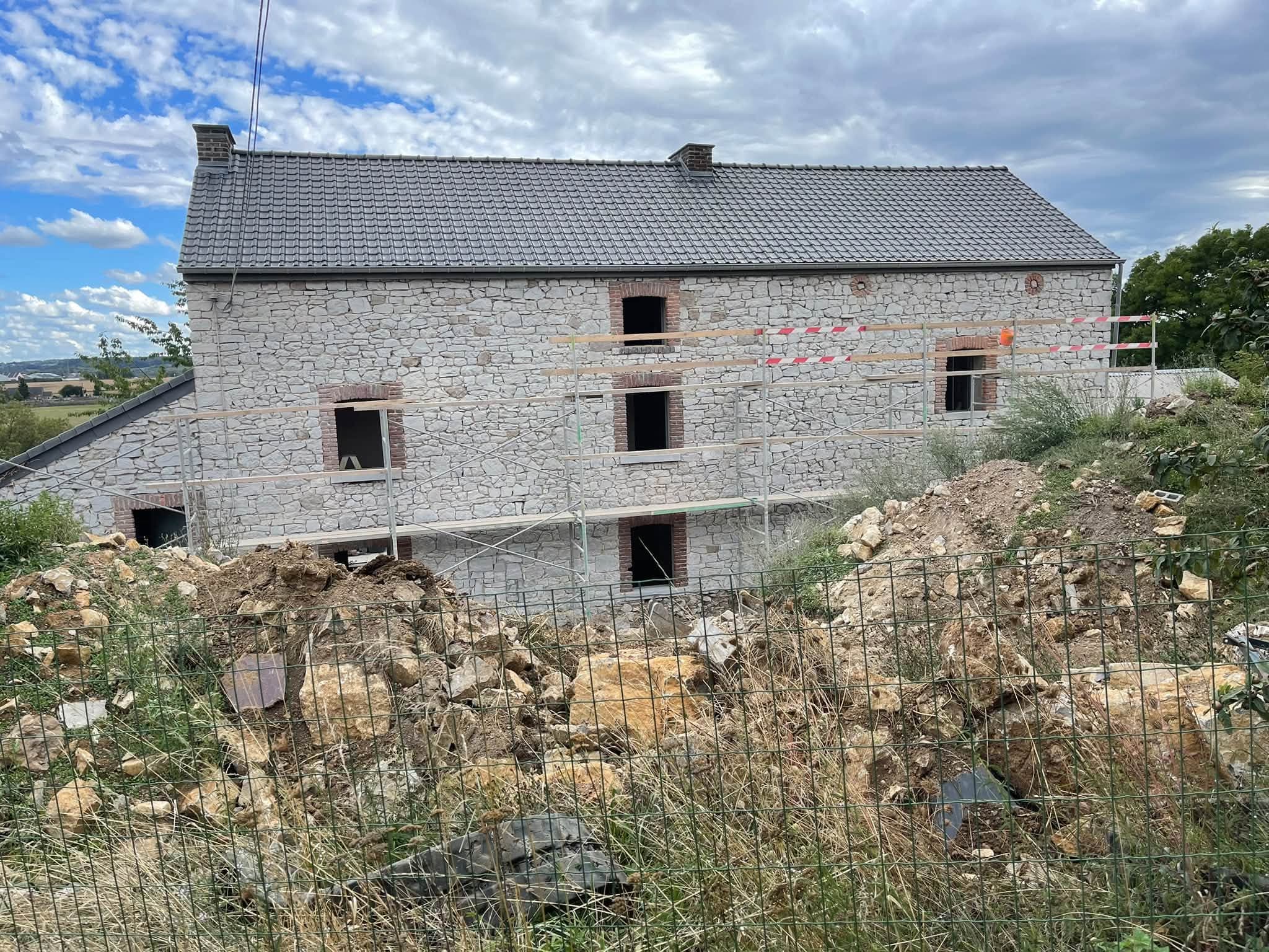 Maison en moellons en cours de restauration, entourée de terre et de pierres